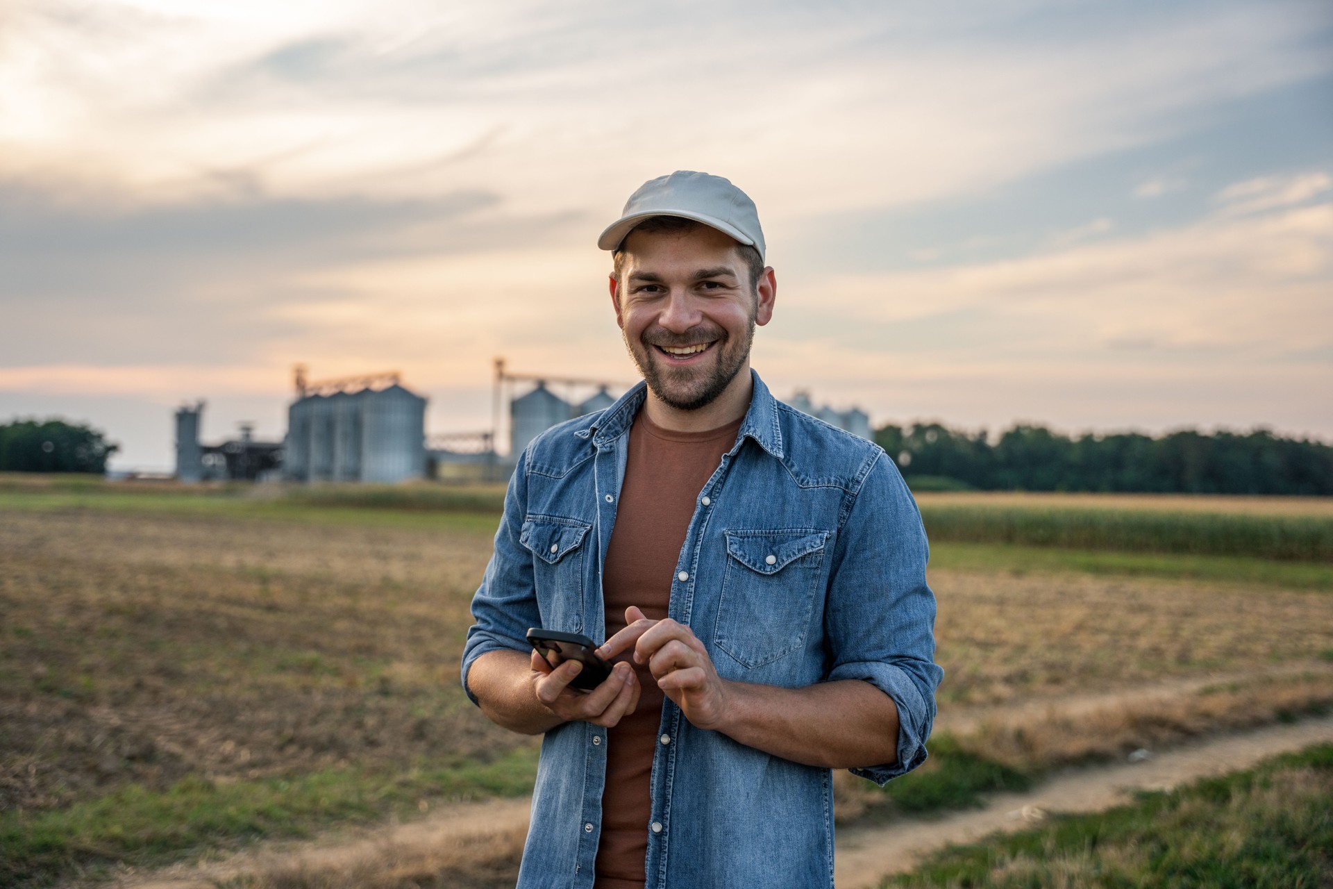 Happy male farmer using mobile phone in field